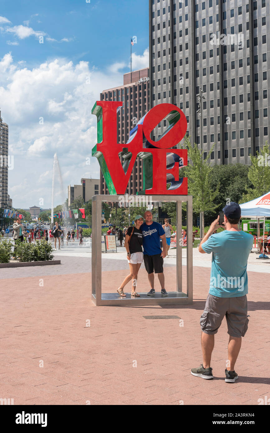 Amore coppia, in vista di un sorridente giovane uomo e donna fotografata sotto la famosa scultura di amore nella JFK Plaza, Philadelphia, Pennsylvania, PA, Stati Uniti d'America Foto Stock