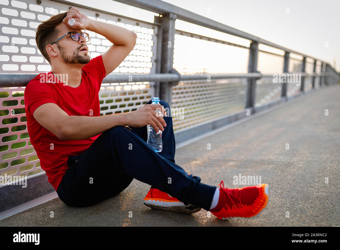 L'uomo runner prendendo una pausa durante il corso di formazione all'esterno. Appoggio del pareggiatore dopo l'esecuzione. Foto Stock