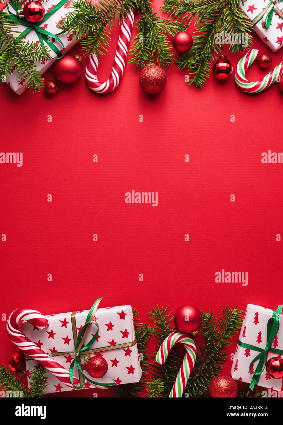 Red Buon Natale e Anno Nuovo sfondo. Cornice decorativa di rami di abete, doni, palle di Natale e candy cane. Il Natale di creep Foto Stock
