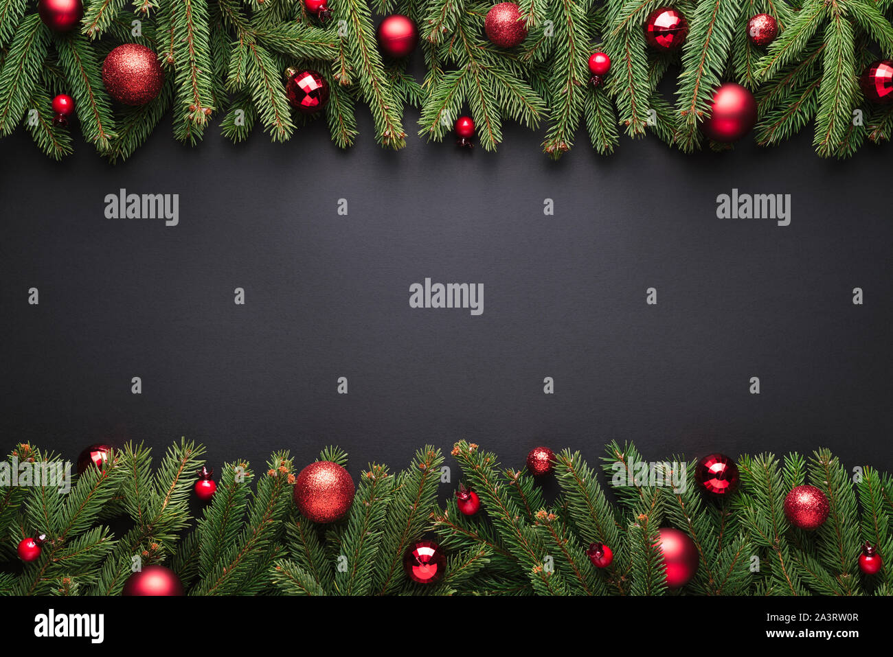 Buon Natale e felice anno nuovo sfondo. Cornice decorativa di rami di abeti e palle di Natale su sfondo nero Foto Stock