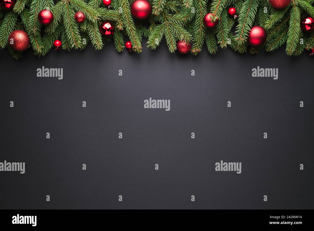 Natale e Anno Nuovo sfondo. Cornice decorativa di rami di abeti e palle di Natale su sfondo nero Foto Stock
