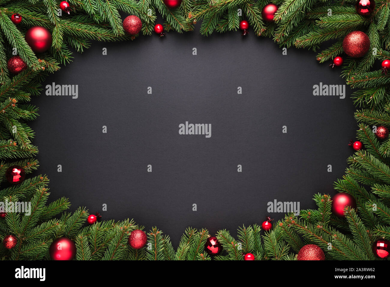 Natale o Capodanno sfondo. Decorativa cornice ovale di rami di abeti e palle di Natale su sfondo nero Foto Stock