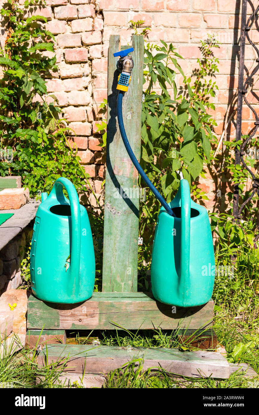 Due 2 turchese innaffiatoi essendo riempito con acqua in giardino Foto Stock