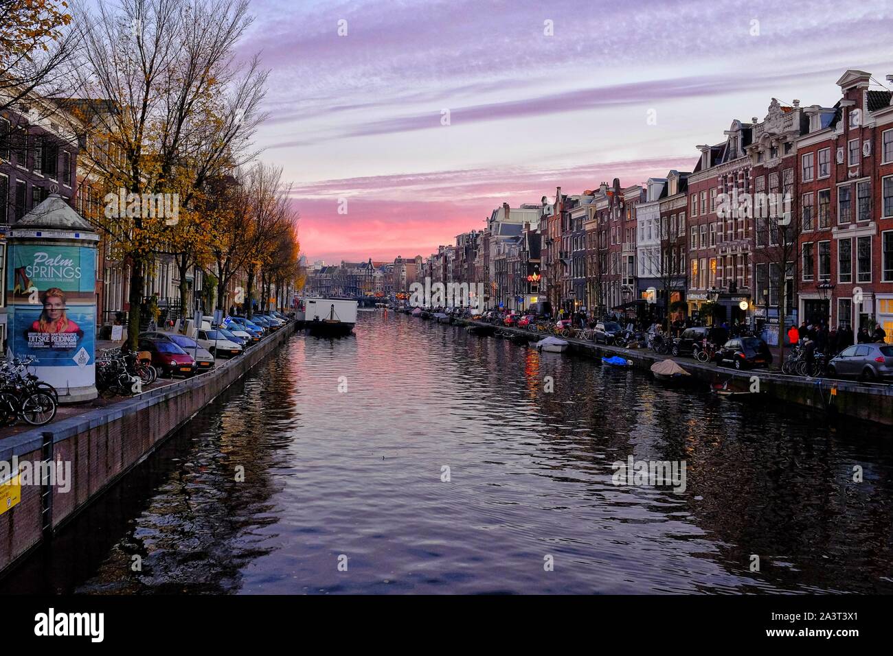 Violetta Cielo di tramonto su canali di Amsterdam ,imbarcazioni turistiche e architettura tradizionale Foto Stock