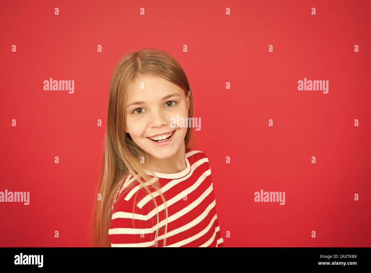 Buona genitorialità. Prodotti per la cura del bambino. La famiglia e l'amore. giorno. Felice bambina su sfondo rosso. piccole bambine. Istruzione scolastica. Infanzia felicità. copia di spazio. Poco d'evasione. Foto Stock