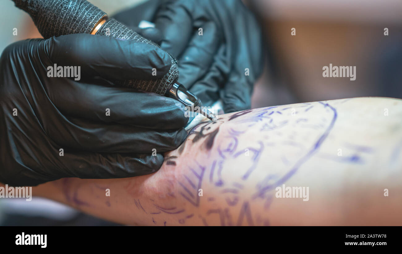 Professional tattoo artist fa un tatuaggio su una giovane mano d'uomo,  close-up. Tattoo Artist