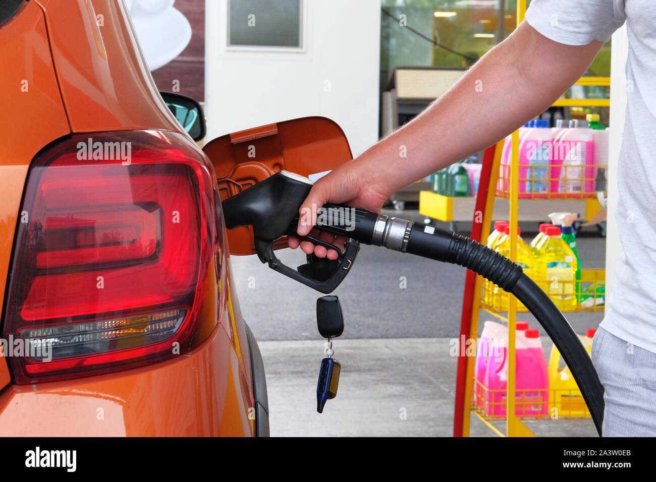 Pompaggio del carburante benzina in arancione auto in una stazione di benzina. Per riempire auto con carburante nella stazione di benzina. Stazione di benzina la pompa. Close up. Foto Stock