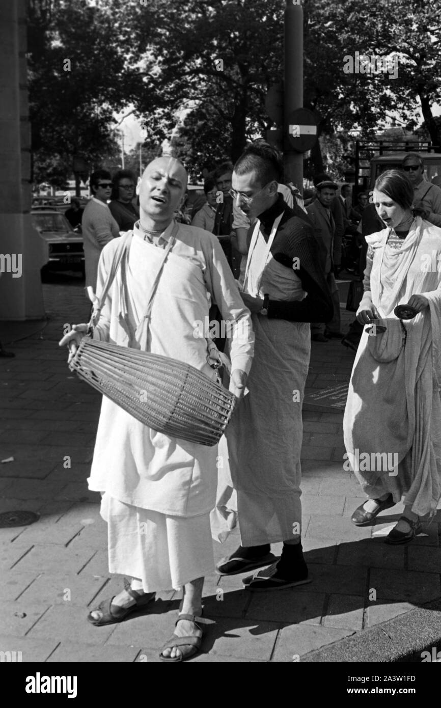 Singend, lobpreisend und trommelnd bewegen sich Hare Krishna Jünger durch die strassen von Amsterdam Niederlande 1971. Il canto, lodando e drumming Hare Krisha seguaci dancing attraverso le strade di Amsterdam, Paesi Bassi 1971. Foto Stock