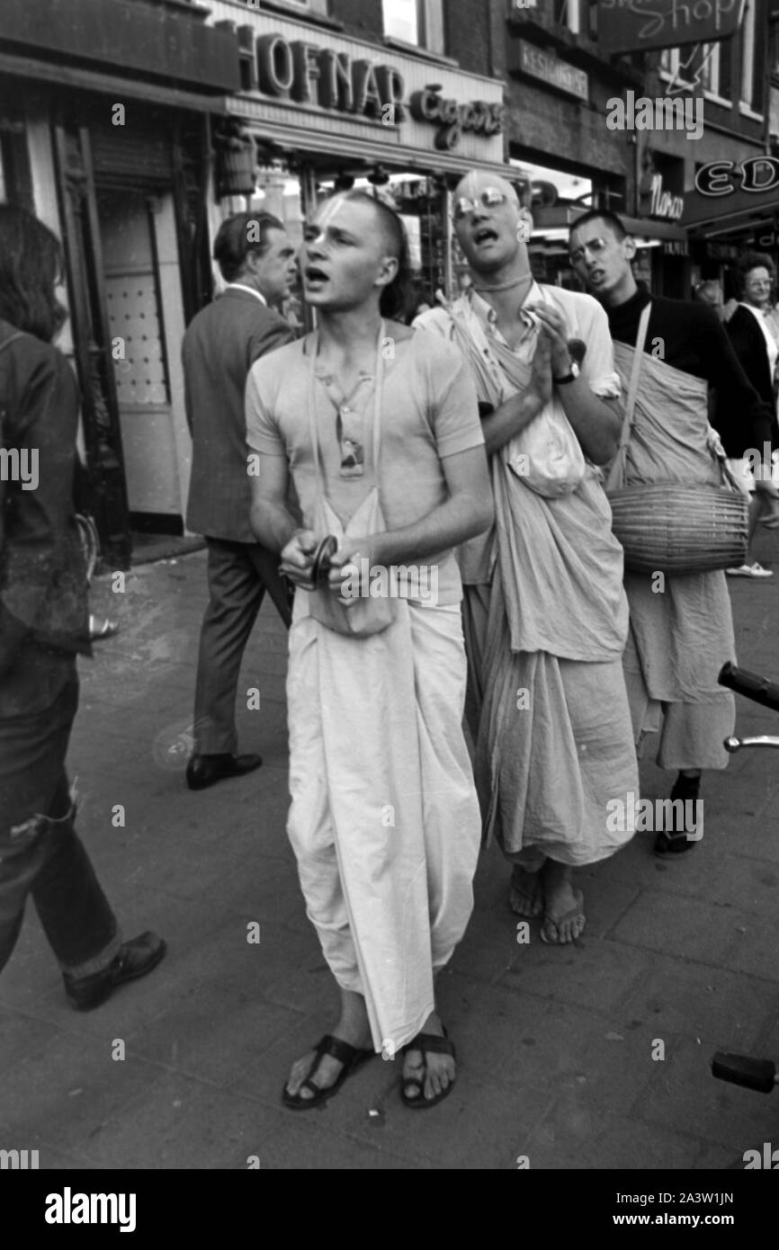 Singend, lobpreisend und trommelnd bewegen sich Hare Krishna Jünger durch die strassen von Amsterdam Niederlande 1971. Il canto, lodando e drumming Hare Krisha seguaci dancing attraverso le strade di Amsterdam, Paesi Bassi 1971. Foto Stock