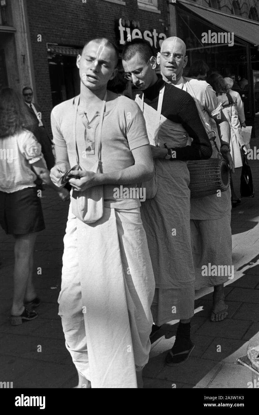 Singend, lobpreisend und trommelnd bewegen sich Hare Krishna Jünger durch die strassen von Amsterdam Niederlande 1971. Il canto, lodando e drumming Hare Krisha seguaci dancing attraverso le strade di Amsterdam, Paesi Bassi 1971. Foto Stock