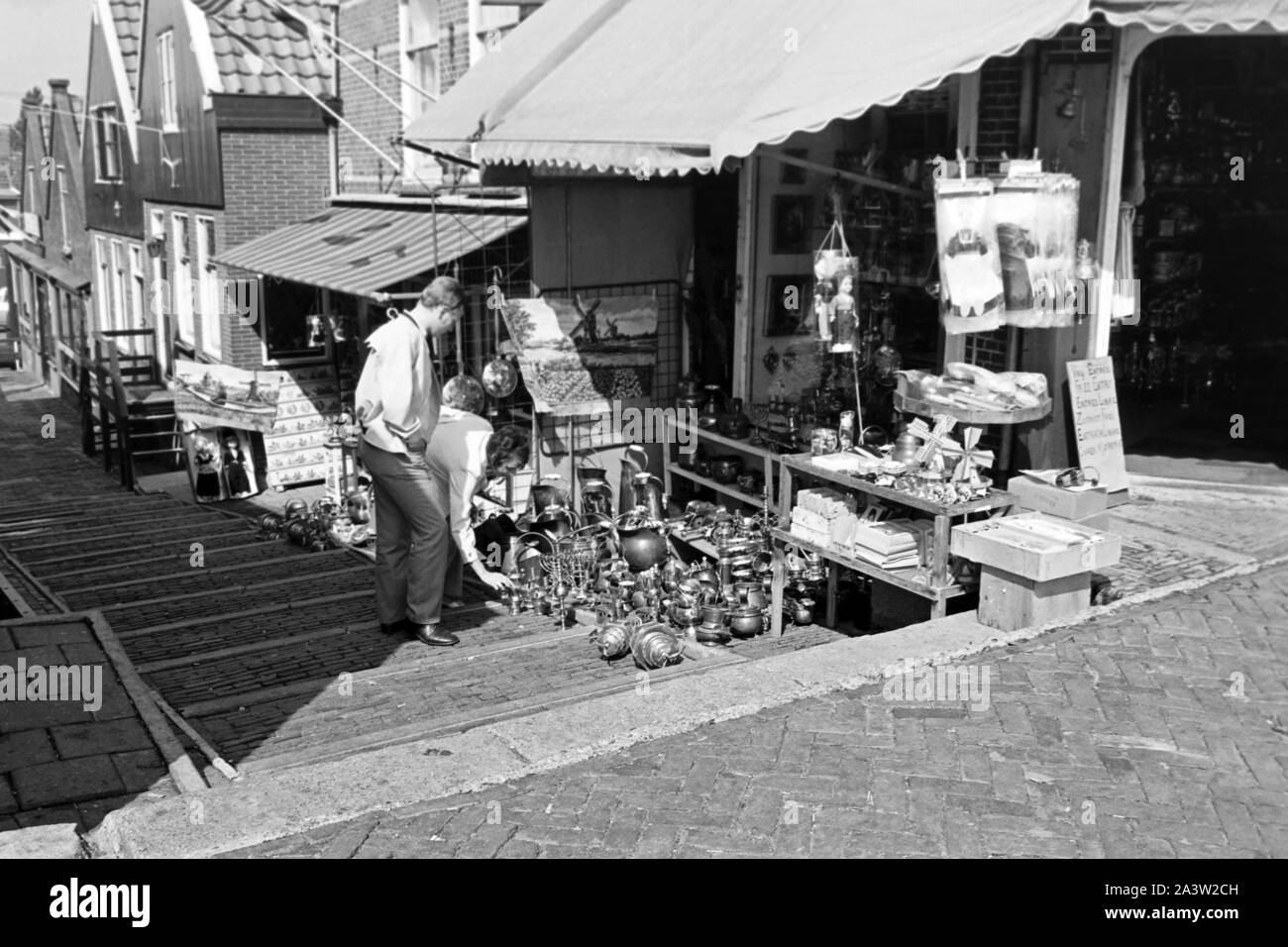Touristen stöbern im Angebot eines Kramladens a Volendam, Niederlande 1971. I turisti a estirpazione le offerte di un negozio di antiquariato a Volendam, Paesi Bassi 1971. Foto Stock