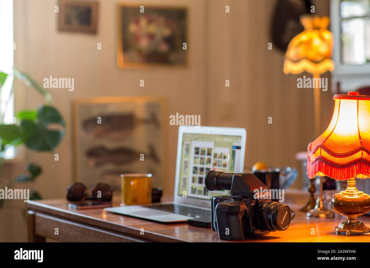 Una vista di un home office con un formato supporto telecamera analogica su un tavolo di fronte a un computer portatile e di altri oggetti vari. Foto Stock