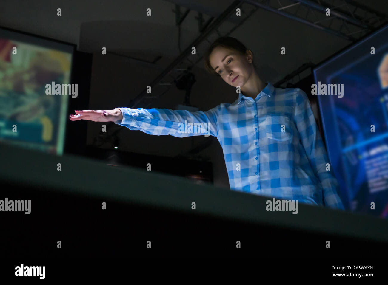 Donna che utilizza la visualizzazione interattiva senza toccare la tecnologia di controllo Foto Stock