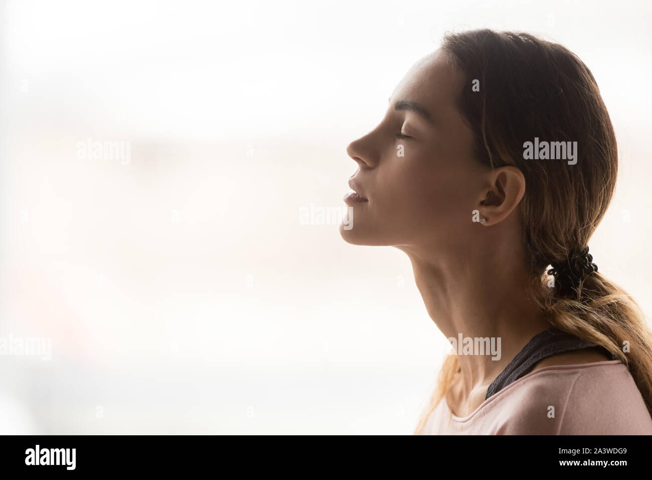 Serena giovane donna prendendo un respiro profondo di aria fresca Foto Stock