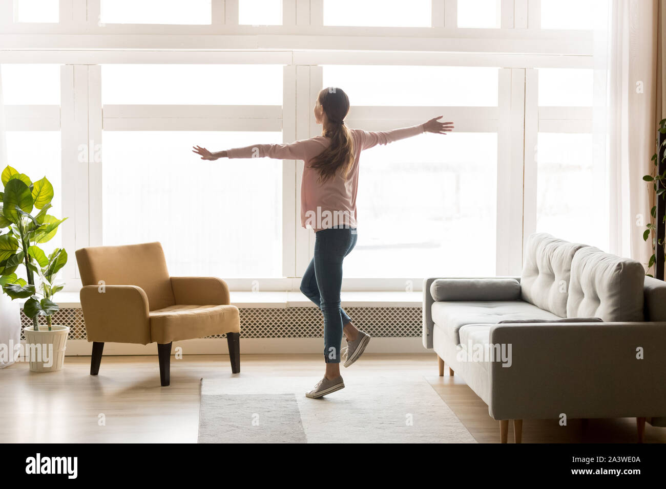 Felice active giovane donna ballo da sola nel soggiorno moderno Foto Stock