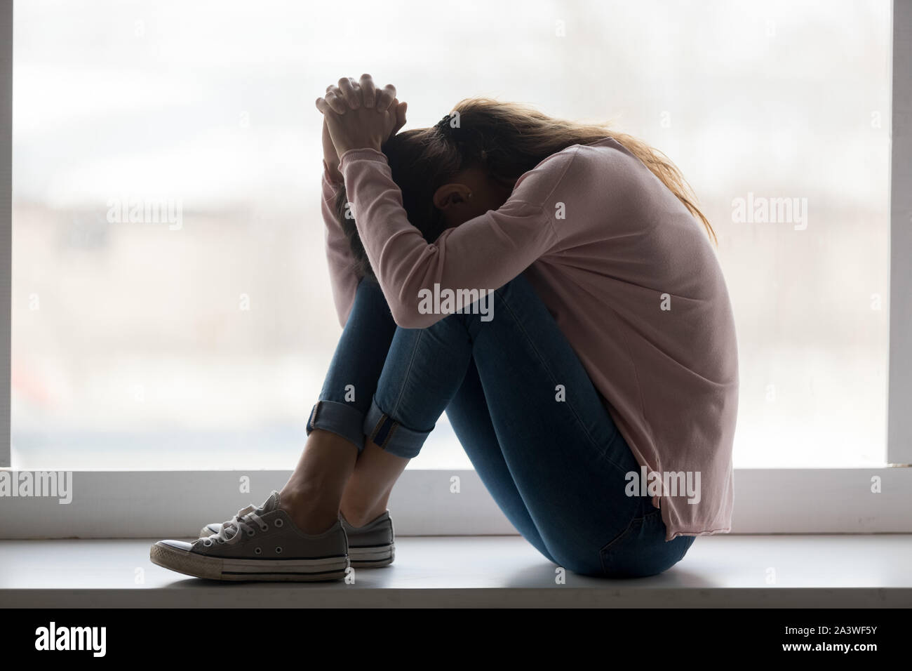 Premuto triste teen ragazza sedersi sul davanzale piangendo a casa Foto Stock