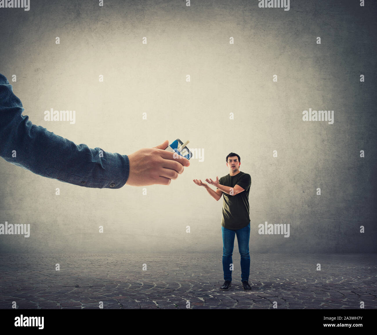 Confuso giovane uomo, mani tese, la ricezione di un pacchetto di sigarette da una persona sconosciuta enorme mano. Illegale di sigarette di contrabbando. Dipendenza e ba Foto Stock