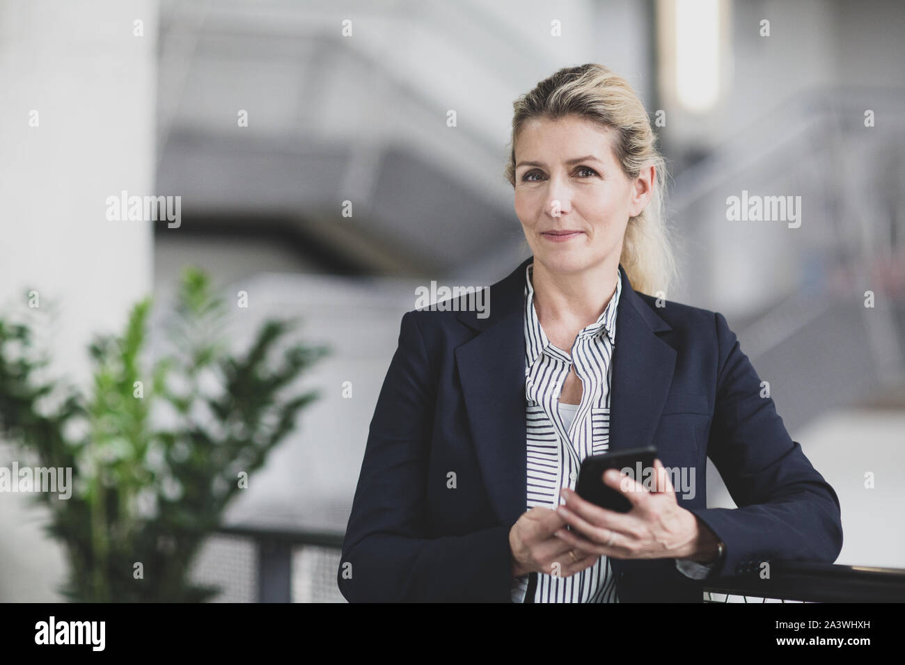 Ritratto di femmina senior business executive tenendo uno smartphone Foto Stock