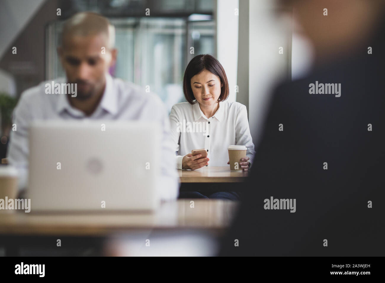 Imprenditrice in un cafÃ© utilizzando uno smartphone Foto Stock