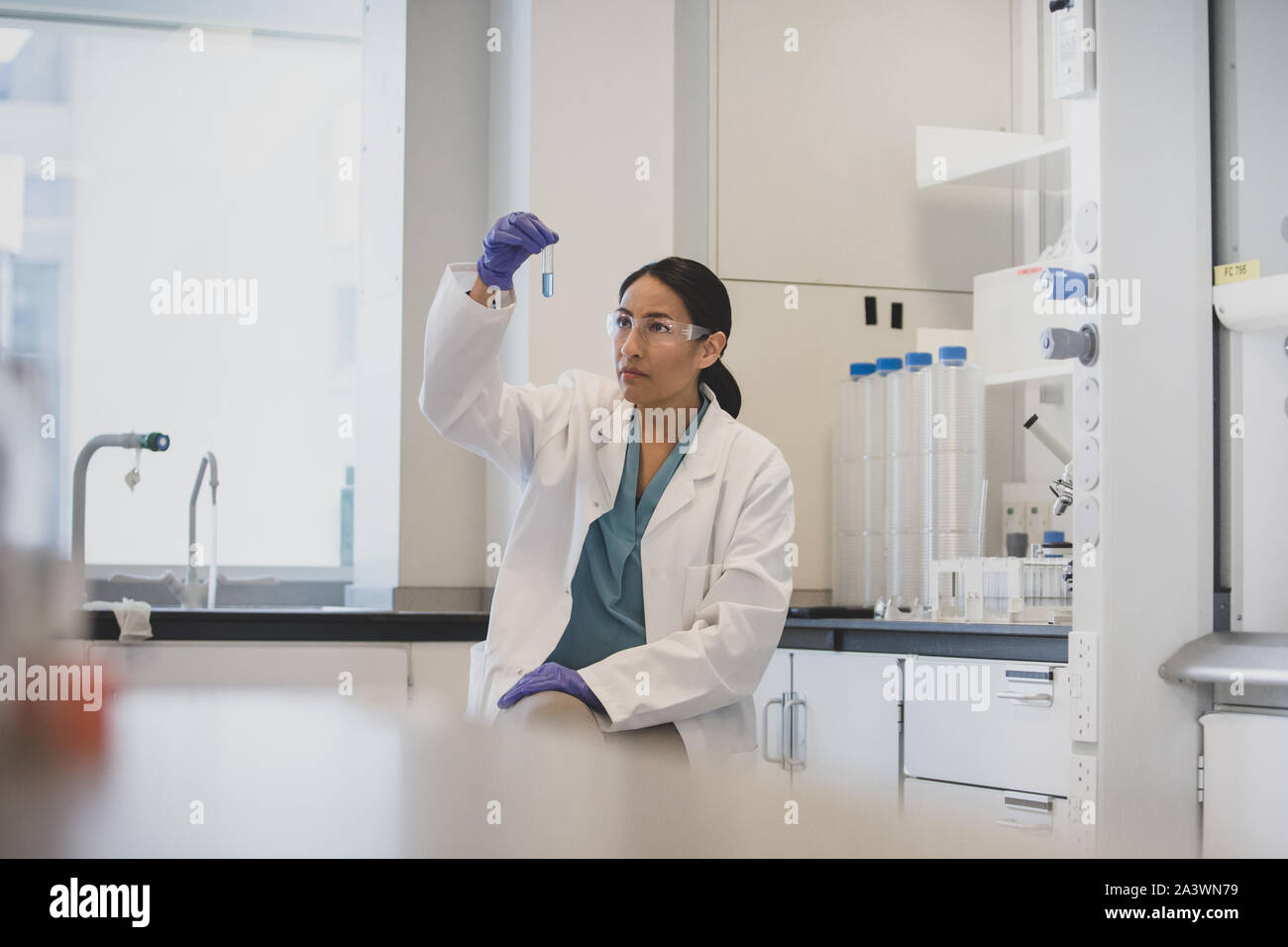 Donna scienziato guardando al tubo di prova in un laboratorio Foto Stock
