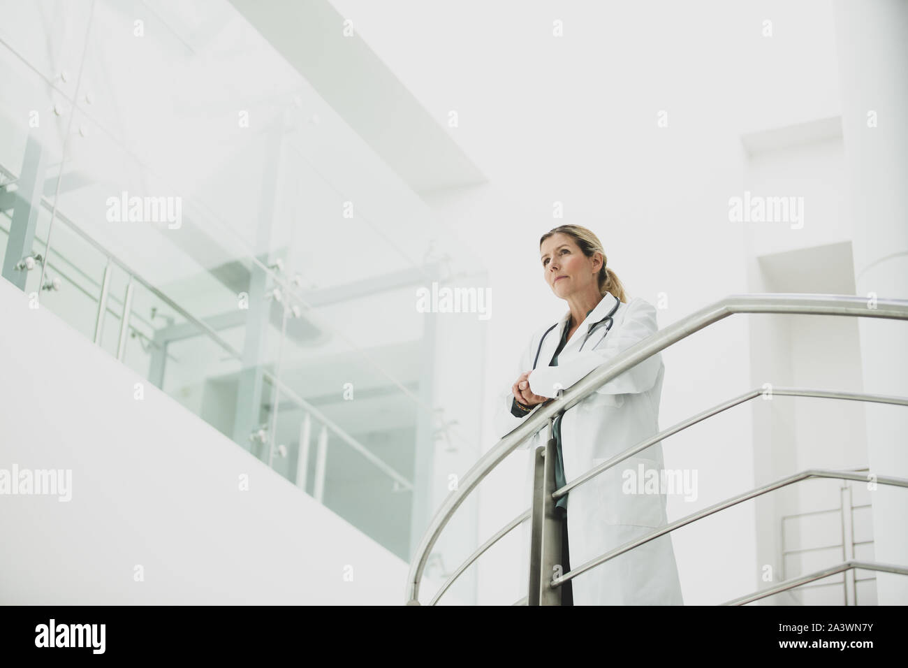 Medico donna in ospedale guardando fuori pensando Foto Stock