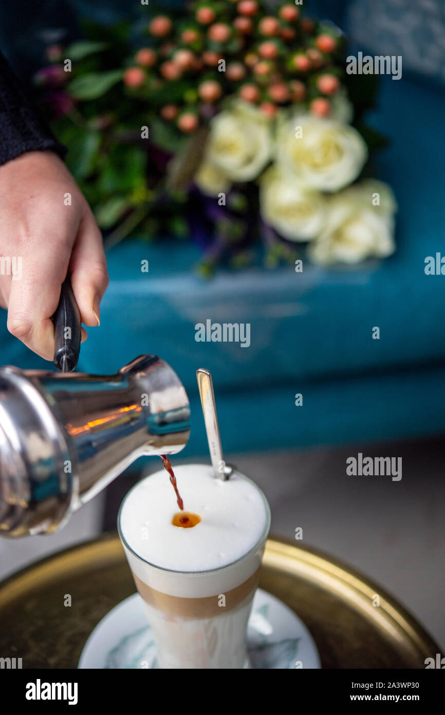 Cameriera una colata di latte fresco il caffè in un bar Foto Stock