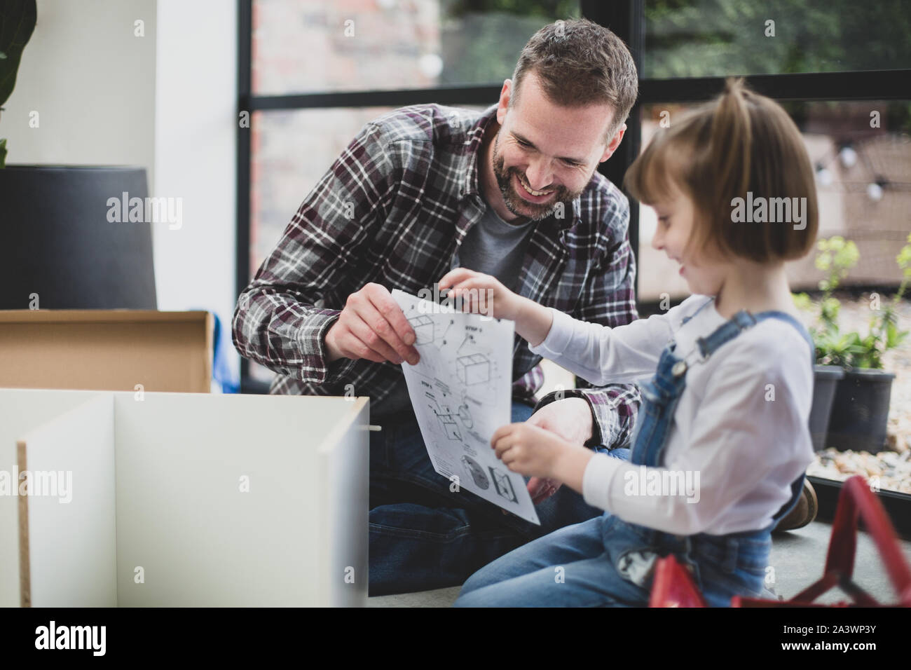 Figlia aiutando il padre con flat pack mobili Foto Stock