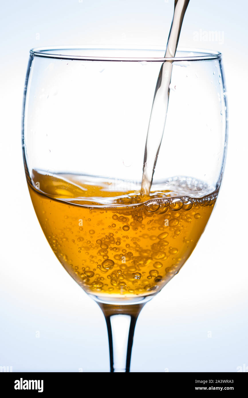 Versando champagne in un bicchiere di vino con uno sfondo bianco. Foto Stock