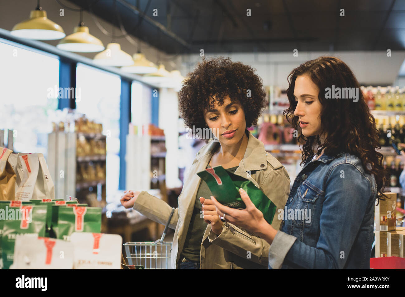 Giovani adulti femmine shopping alimentare in un negozio di alimentari Foto Stock