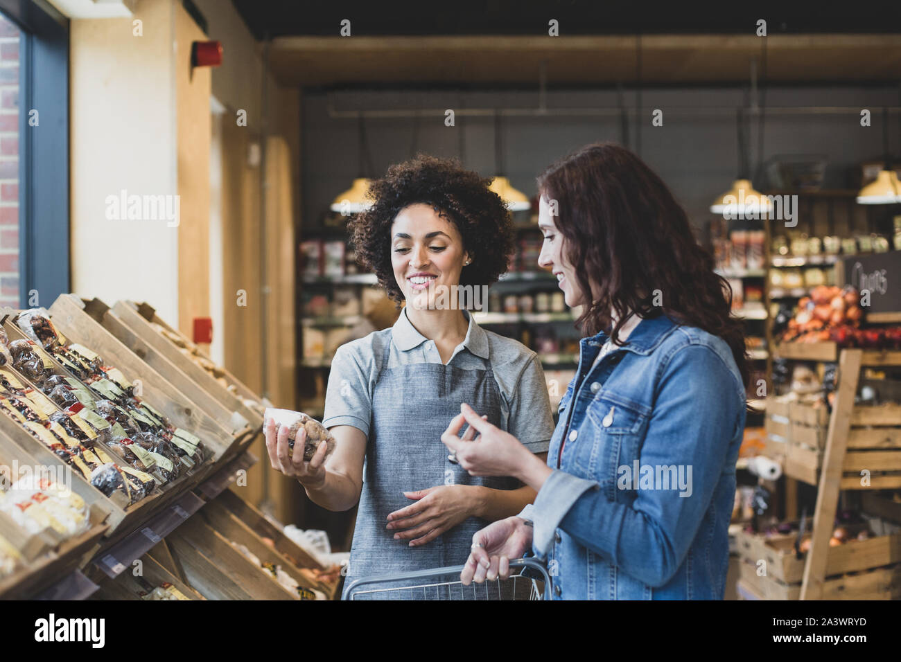Assistente di vendita aiutando il cliente in un negozio di alimentari Foto Stock