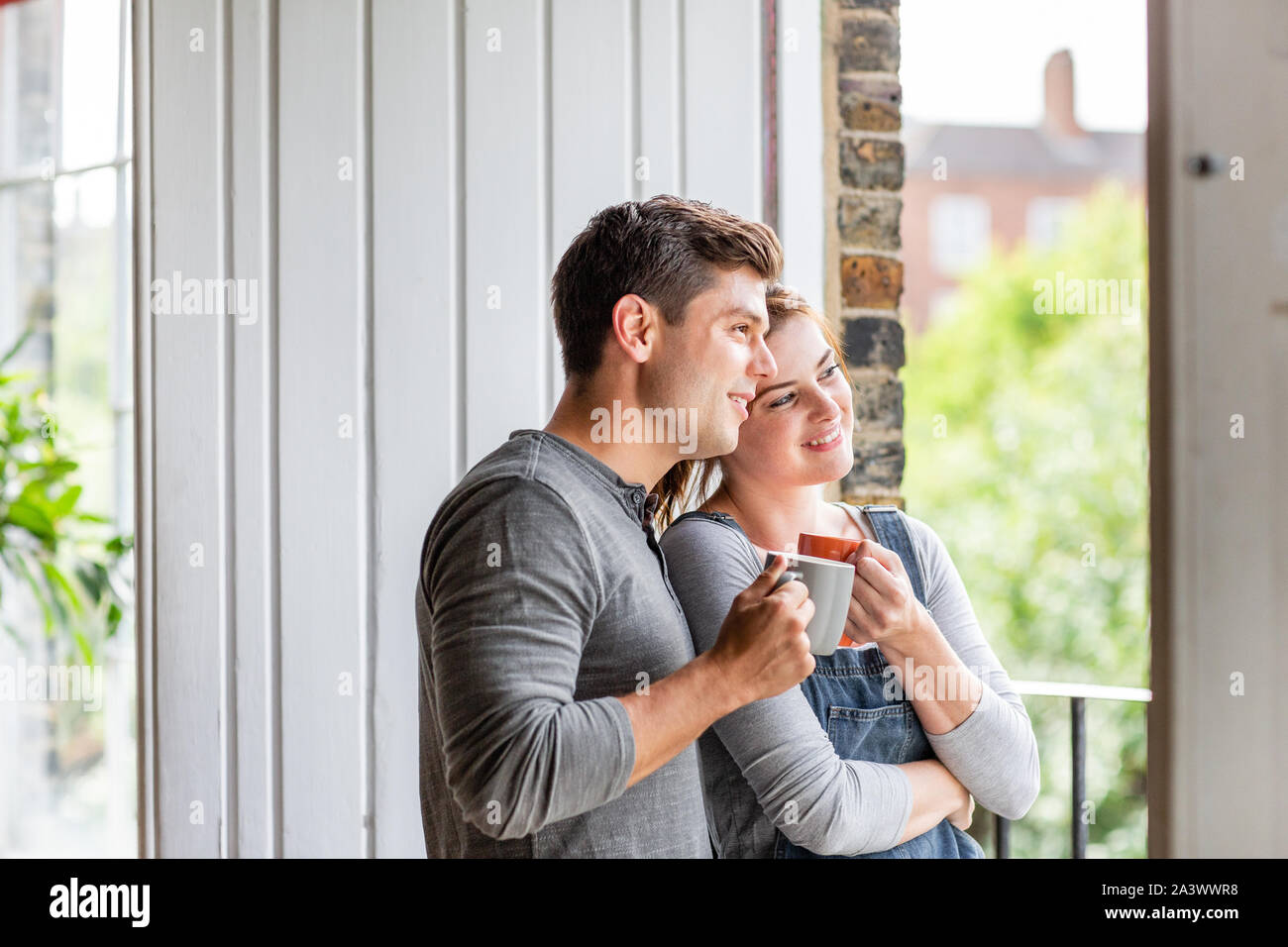 Giovane adulto giovane guardando fuori della finestra nella nuova casa Foto Stock