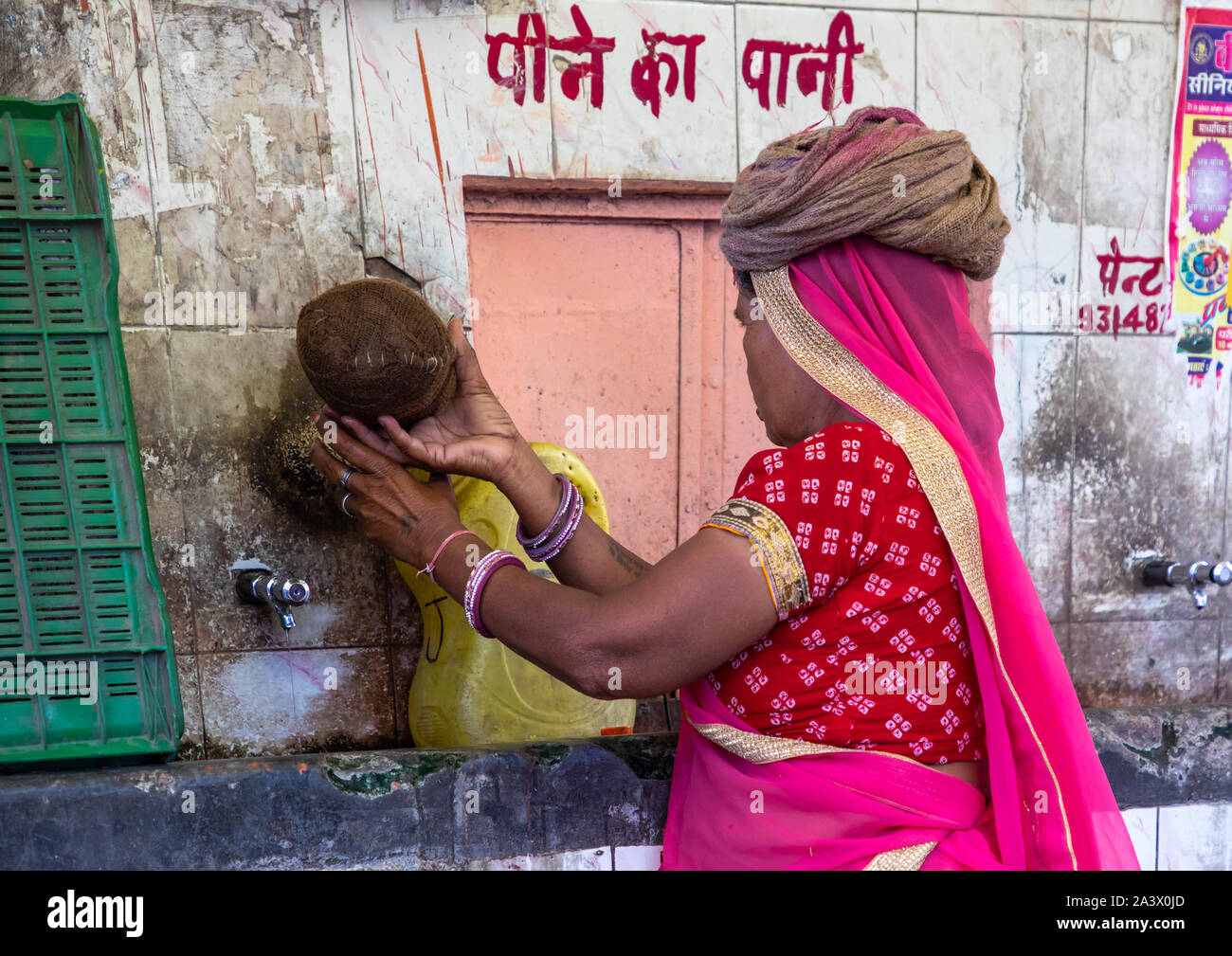 Donna indiana a raccogliere acqua in strada durante ther onda di calore, Rajasthan, a Jaipur, India Foto Stock