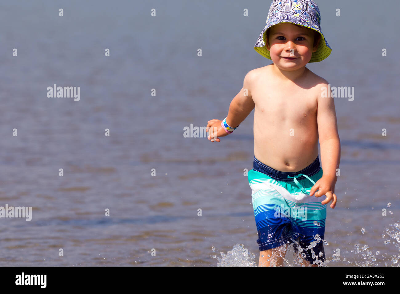 Giovane maschio bambino in esecuzione e schizzi su una spiaggia. Foto Stock