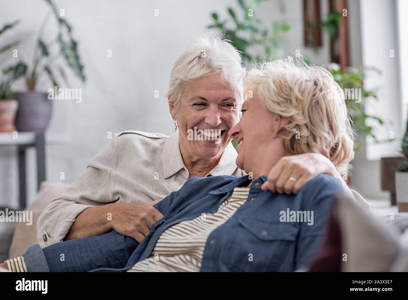 Coppia lesbica giovane a casa sul divano Foto Stock