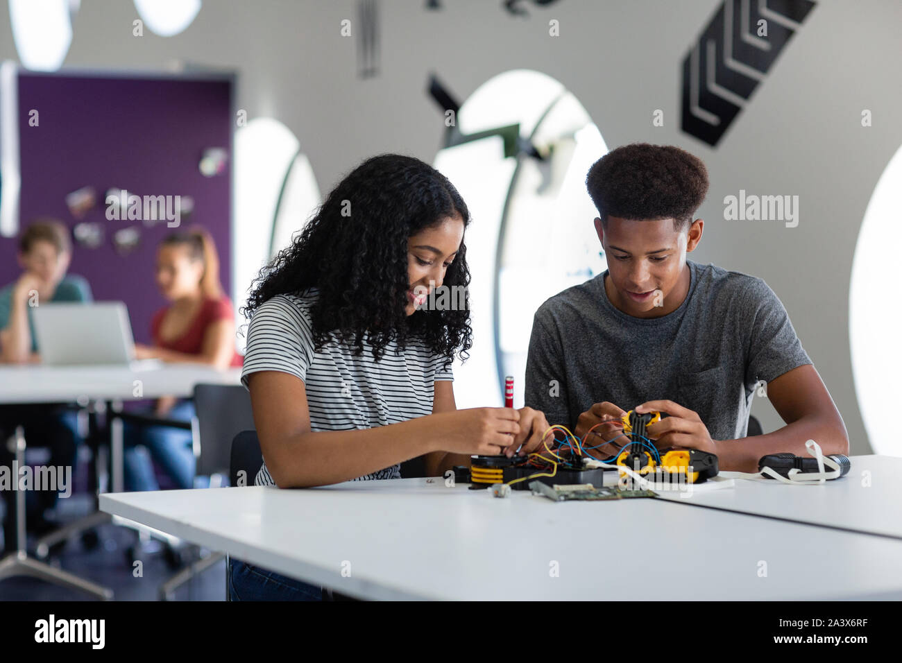 Alta scuola gli studenti che lavorano su un braccio robotico in classe Foto Stock