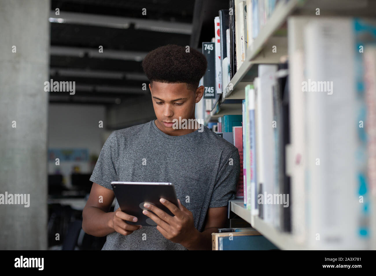 Alta scuola americana africana studente maschio studiando con tavoletta digitale in libreria Foto Stock