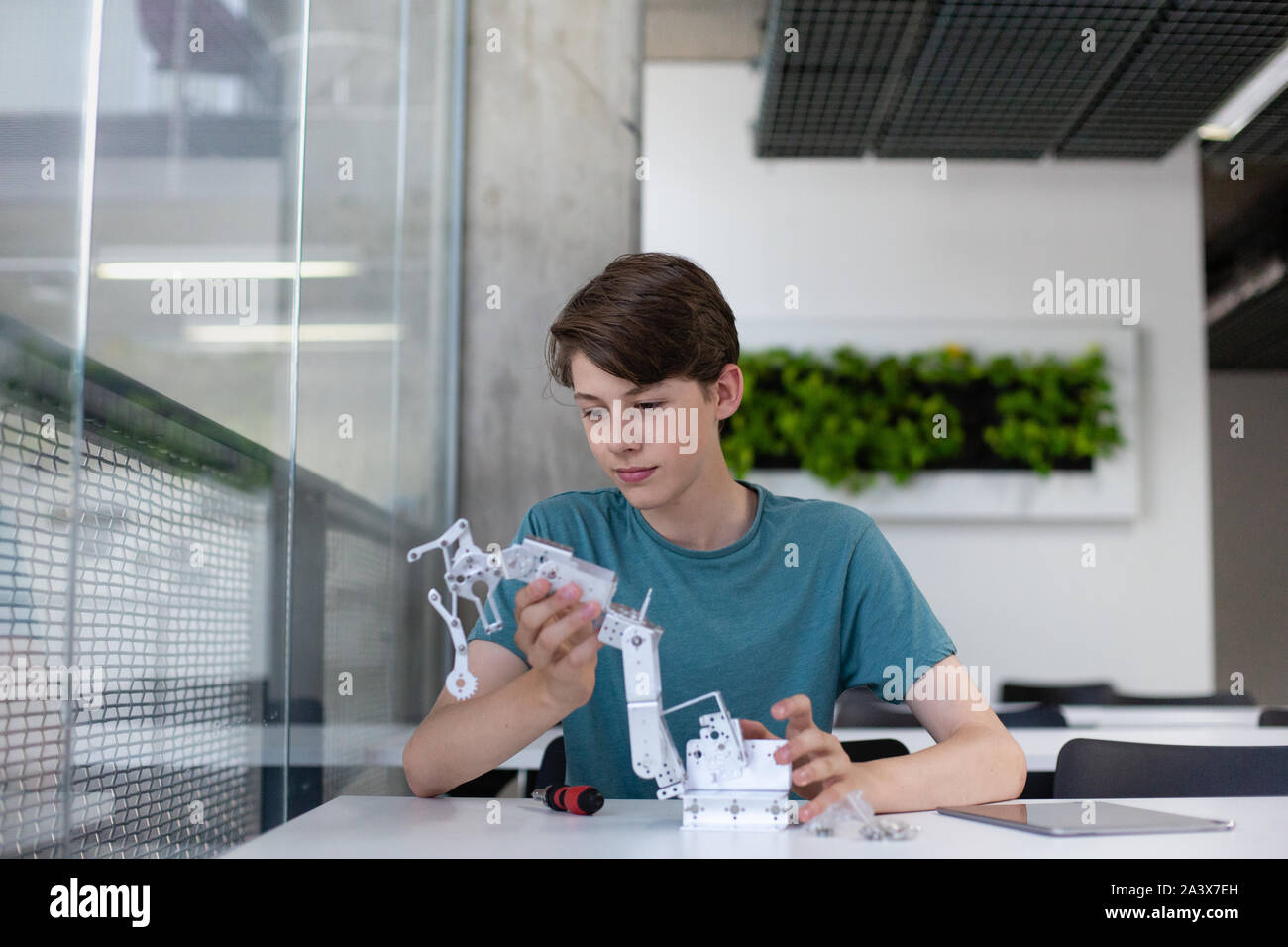 Studente di scuola superiore al lavoro su un braccio robotico in classe Foto Stock