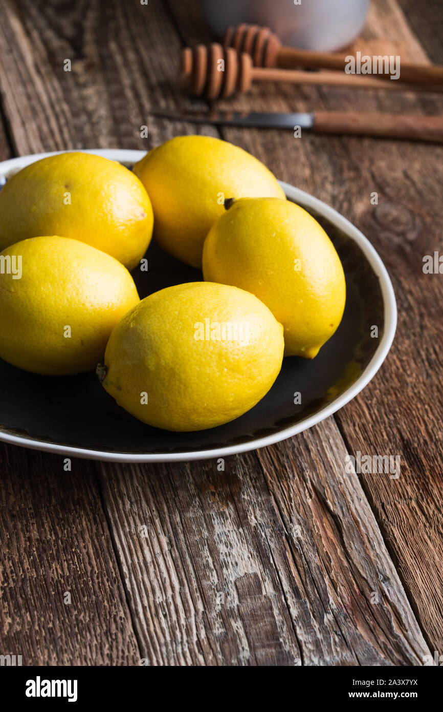 Close-up di limone fresco frutta sulla piastra rurale, la preparazione di autunno bevanda calda sul tavolo di legno a casa, stagionale ancora in vita, il fuoco selettivo Foto Stock