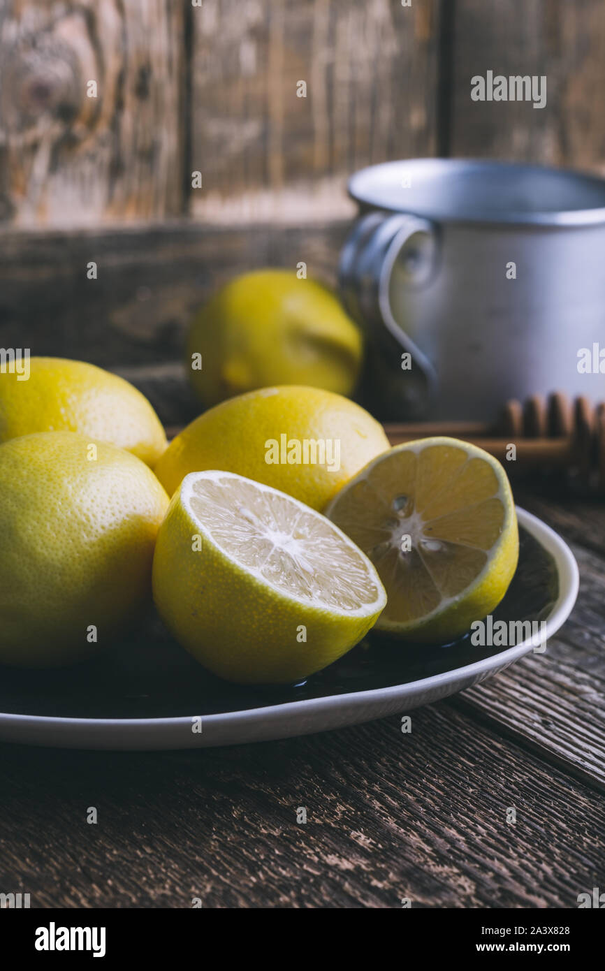 Close-up di limone fresco frutta sulla piastra rurale, la preparazione di autunno bevanda calda sul tavolo di legno a casa, stagionale ancora in vita, il fuoco selettivo Foto Stock