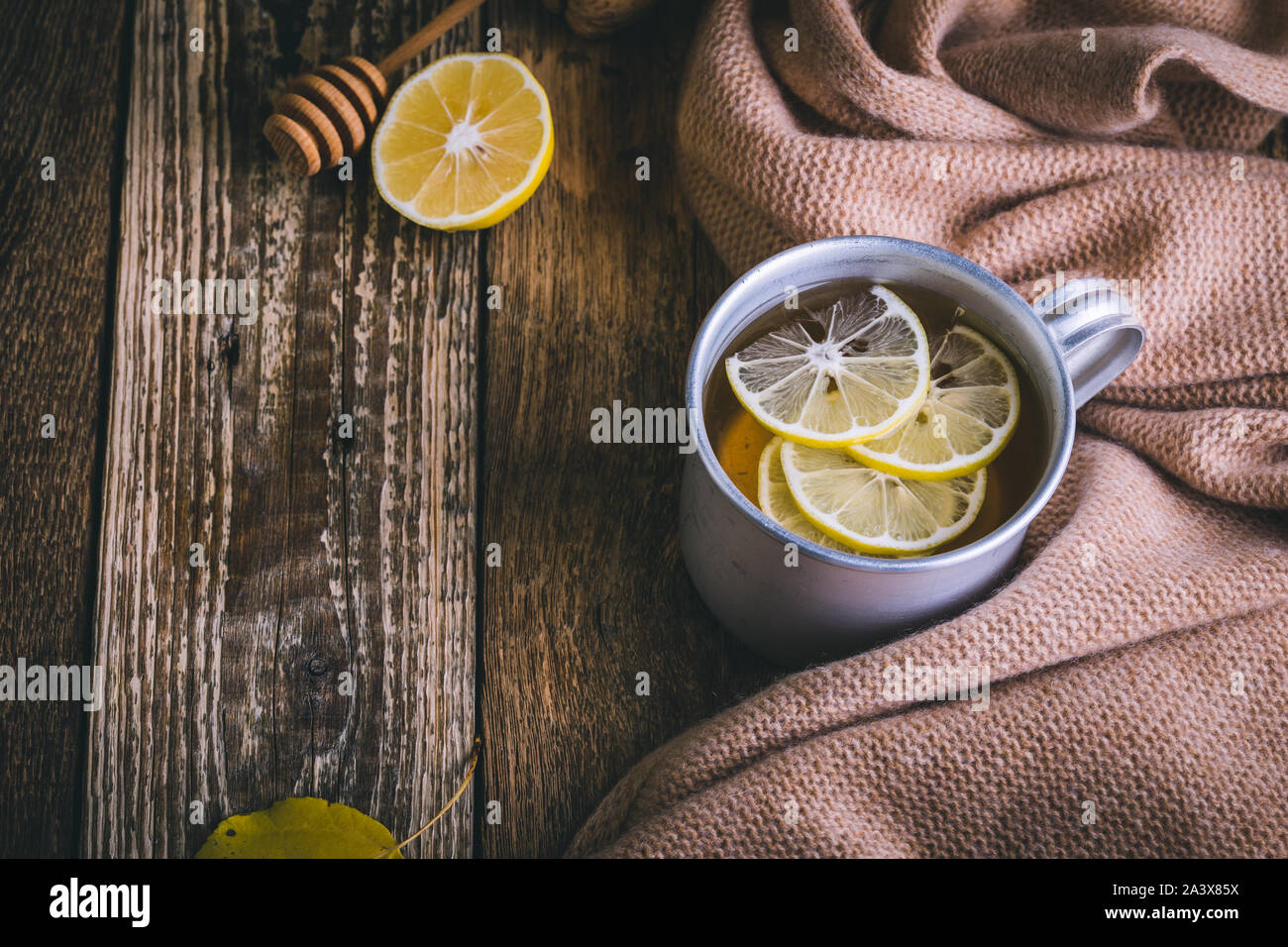 Il tè caldo e limone fresco sulla tavola di legno, autunno tea time. Il Natale o il giorno del Ringraziamento caldo e accogliente bevanda calda e sciarpa di lana, close up Foto Stock