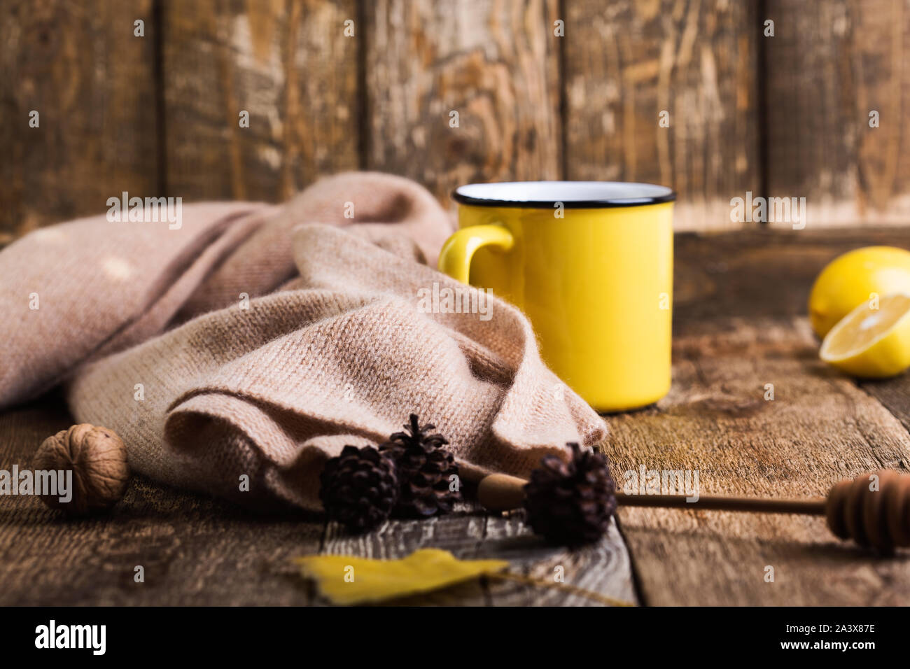 Il tè caldo in giallo mug e limone fresco sul tavolo di legno, autunno tea time. Il Natale o il giorno del Ringraziamento caldo e accogliente bevanda calda e sciarpa di lana, clos Foto Stock