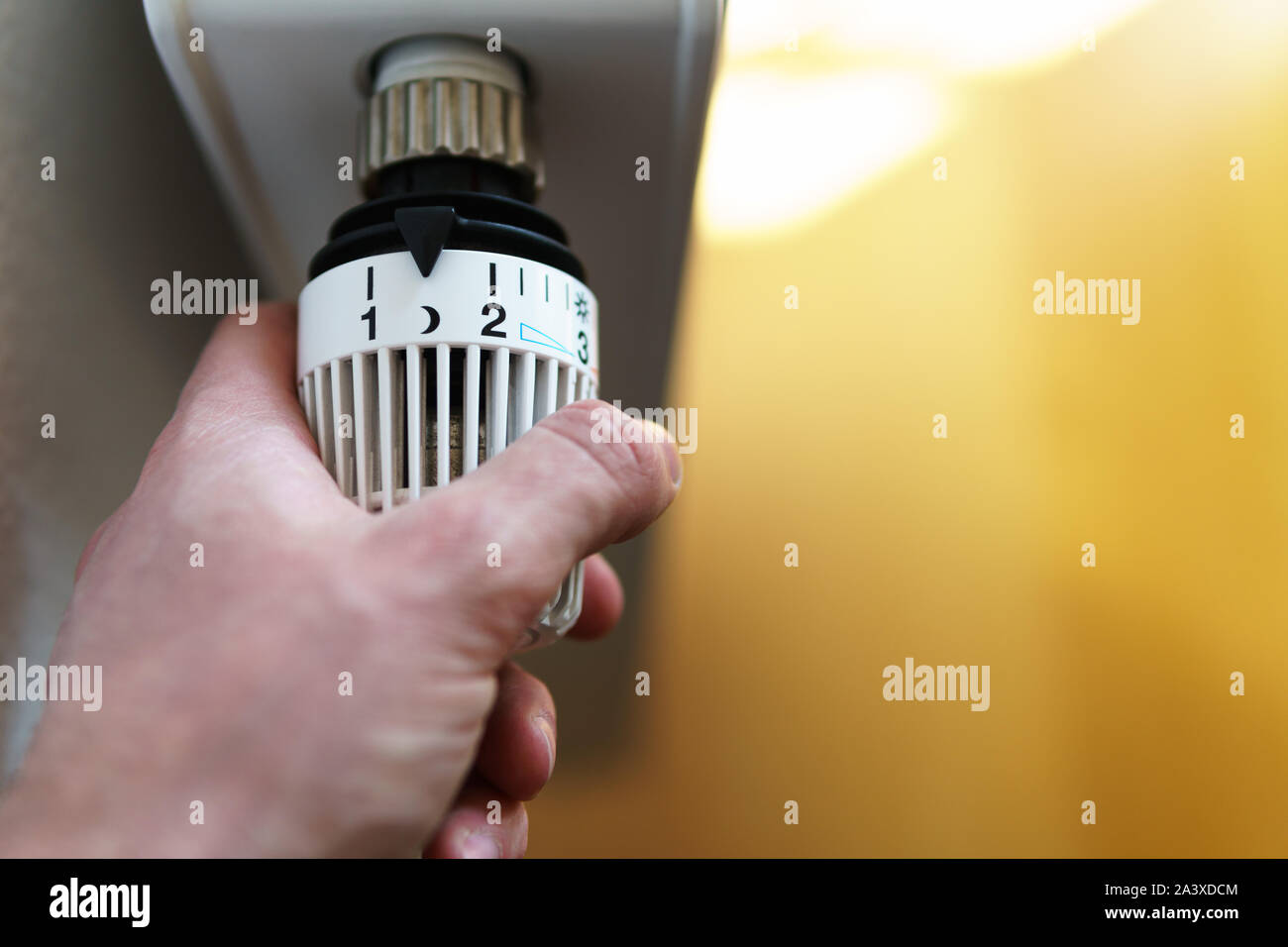 Mano di uomo regolazione valvola del termostato del radiatore fino alla luna (notte) icona, simbolo per risparmiare soldi a spese di riscaldamento o impostazione bassa temperatura, closeu Foto Stock