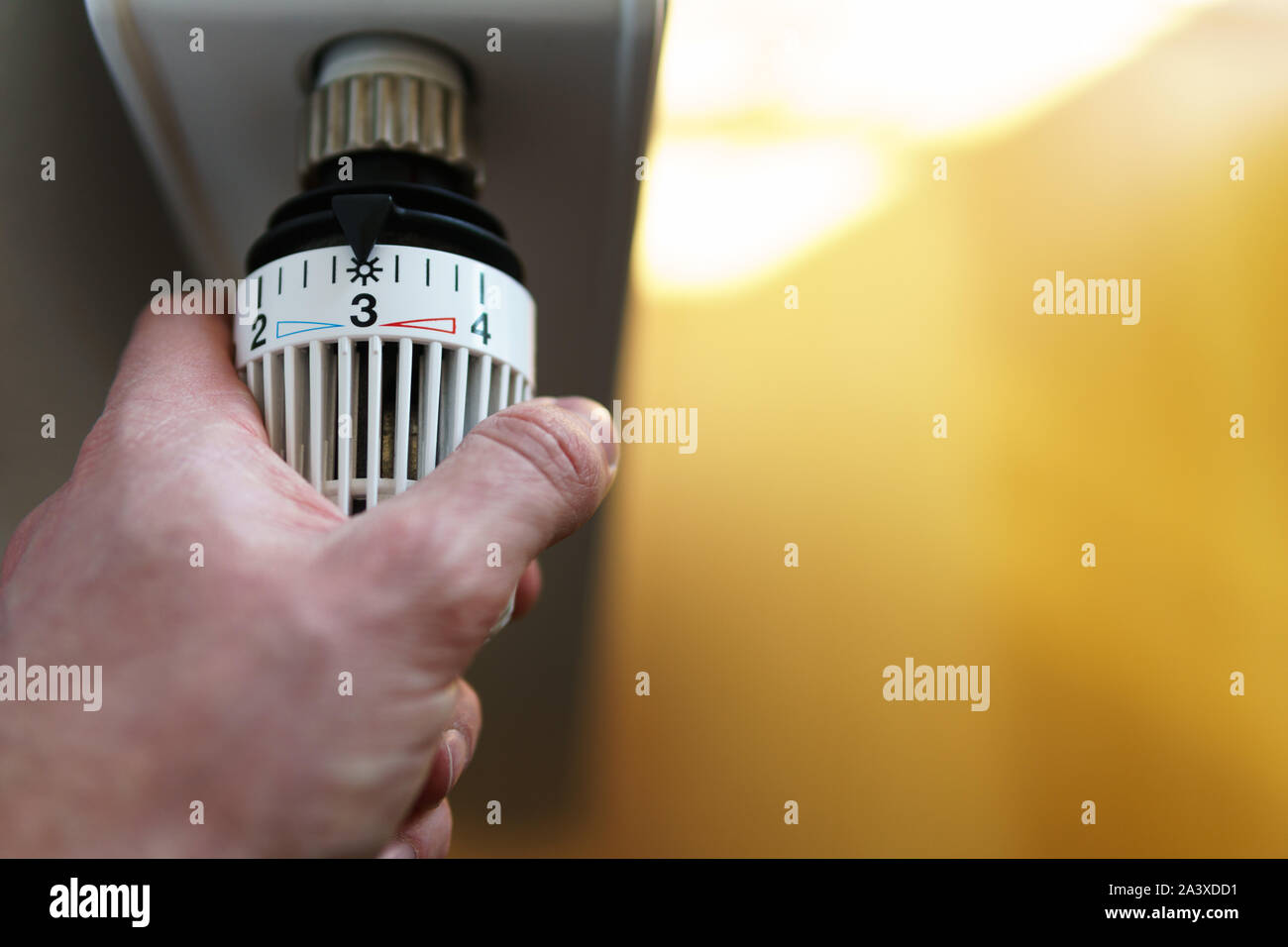 Mano di uomo regolazione valvola del termostato del radiatore al numero tre icona (posizione centrale), simbolo per risparmiare soldi a spese di riscaldamento o la temperatura media Foto Stock
