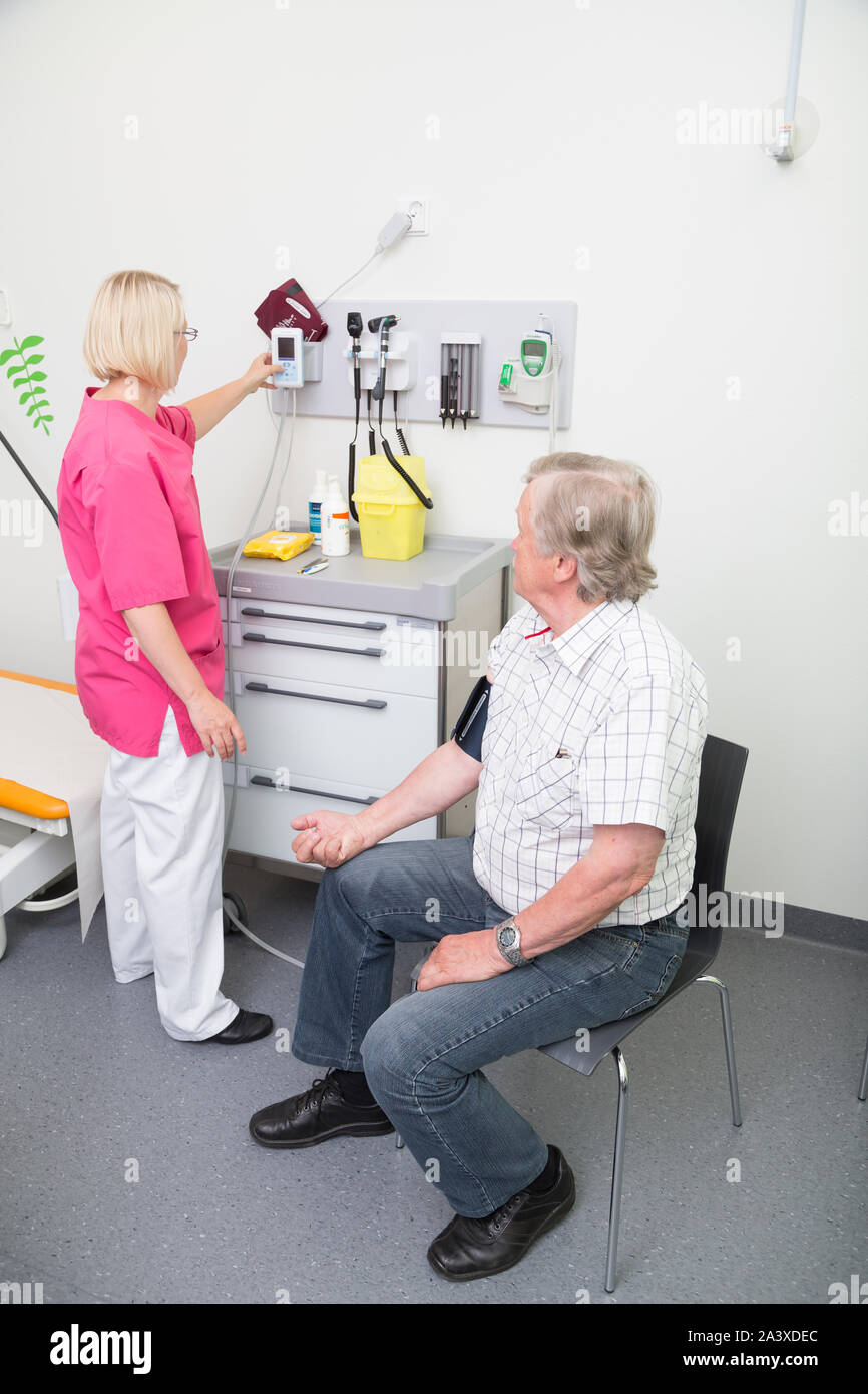 Femmina infermiera registrata la misura della pressione del sangue di un uomo anziano in un ospedale Foto Stock