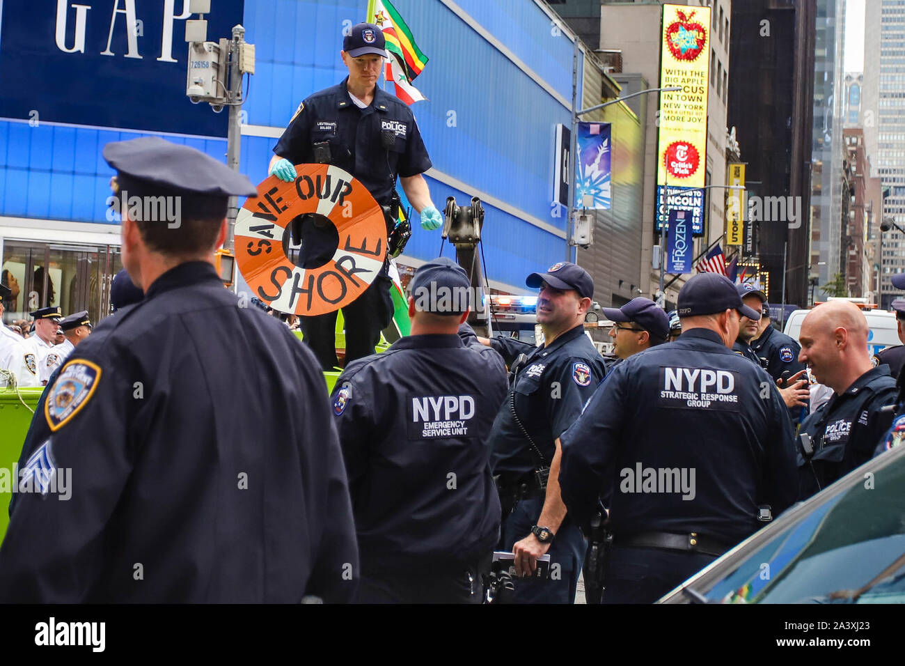 New York, Stati Uniti d'America. 10 ottobre, 2019. La polizia si riuniranno presso la caviglia di una piccola barca a vela che è stato sospeso in Times Square come parte di una protesta da parte del gruppo ambientalista estinzione della ribellione del 10 ottobre 2019 nella città di New York. Come turisti e Newyorkesi guardare, le vittime sono stati arrestati mentre i manifestanti di escalation di modifica bloccati o vittime della tratta di esseri umani in midtown Manhattan. Il gruppo sta protestando il cambiamento climatico durante tutta la settimana in tutta la città di New York e in diversi altri luoghi in tutto il mondo. Credito: Brasile Photo Press/Alamy Live News Foto Stock