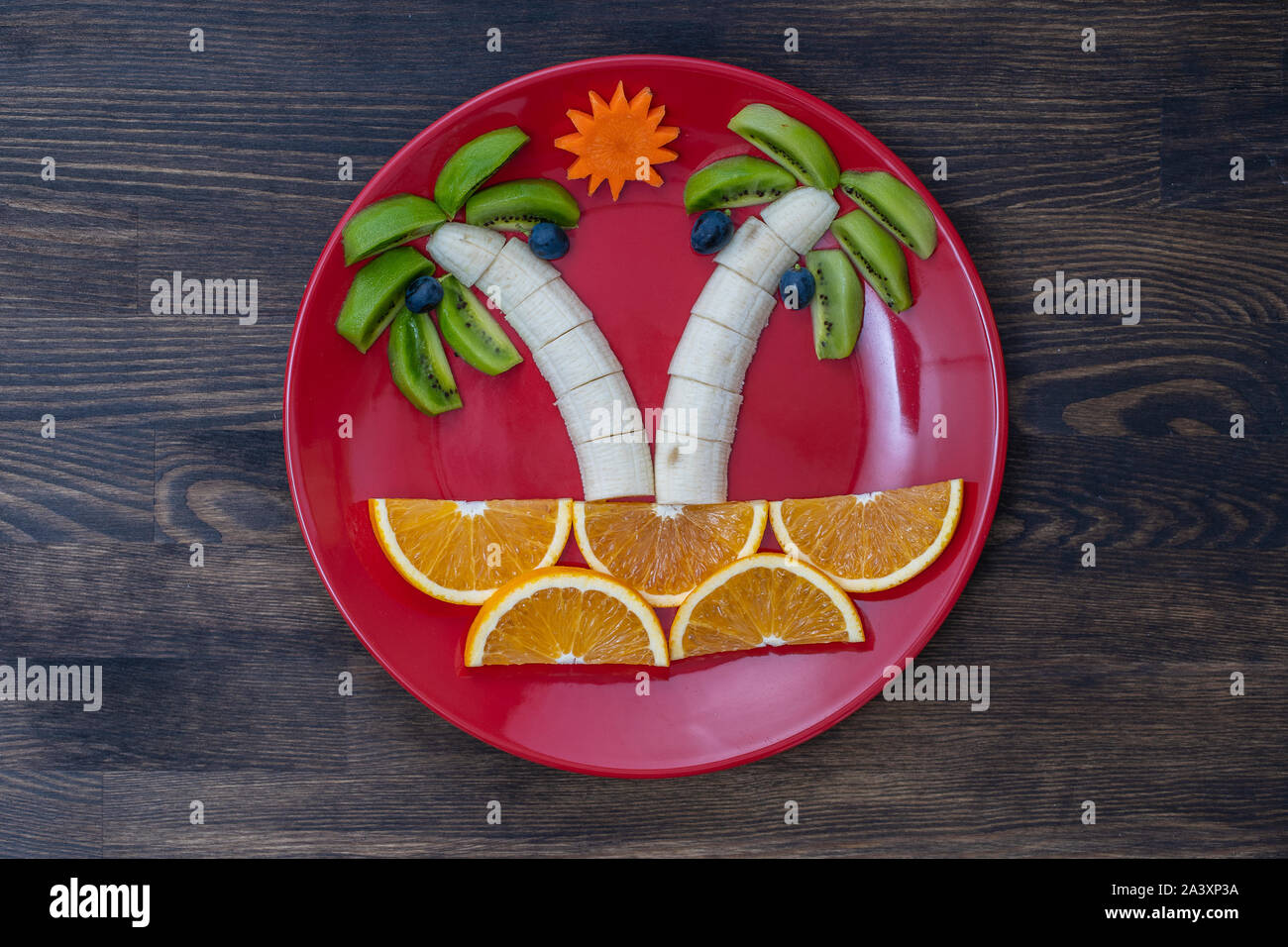 Creative dessert di frutta con kiwi, banana, uva, carota e arancione. Concetto di alimenti per bambini. Divertimento e sana insalata di frutta per bambini. Palme forma resa Foto Stock