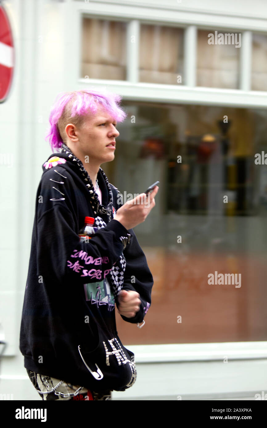Capelli magenta di gioventù con smart-phone IN LINCOLN CITY HIGH STREET Foto Stock