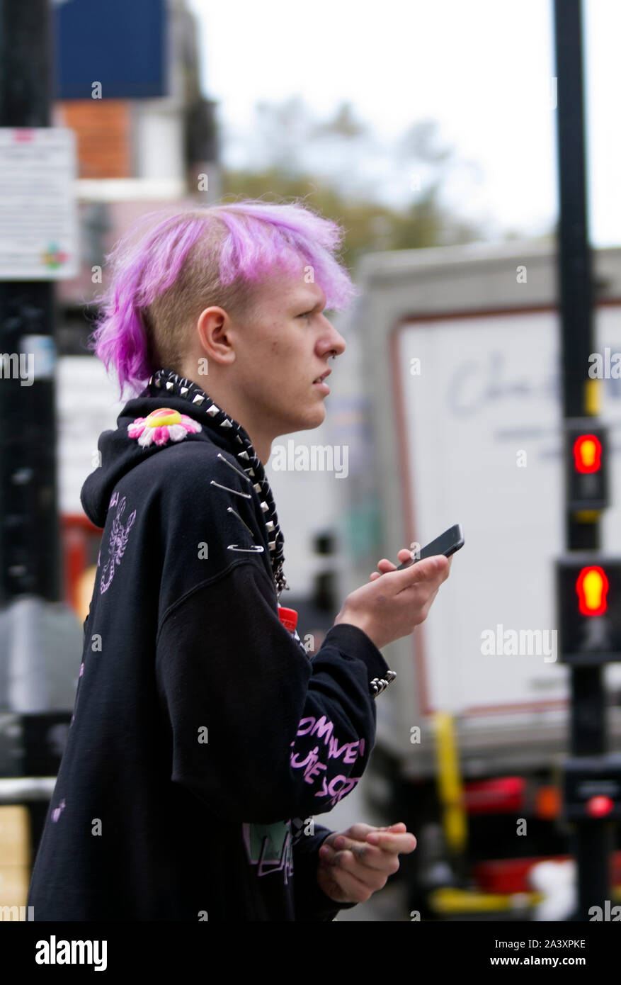 Capelli magenta di gioventù con smart-phone IN LINCOLN CITY HIGH STREET Foto Stock