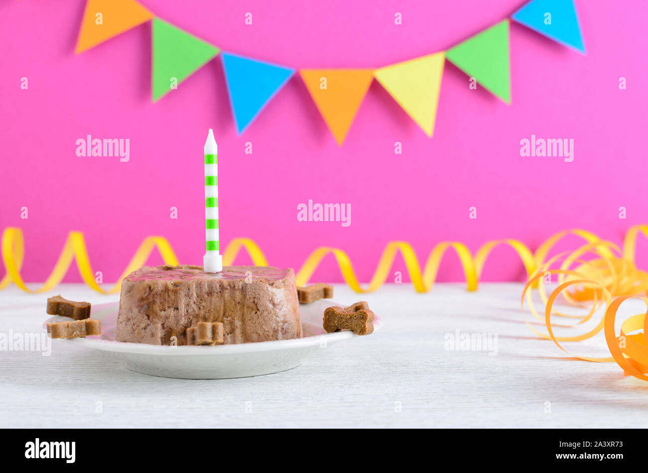 Buon compleanno torta per il cane da alimento umido e tratta con candela sulla parte rosa sullo sfondo Foto Stock
