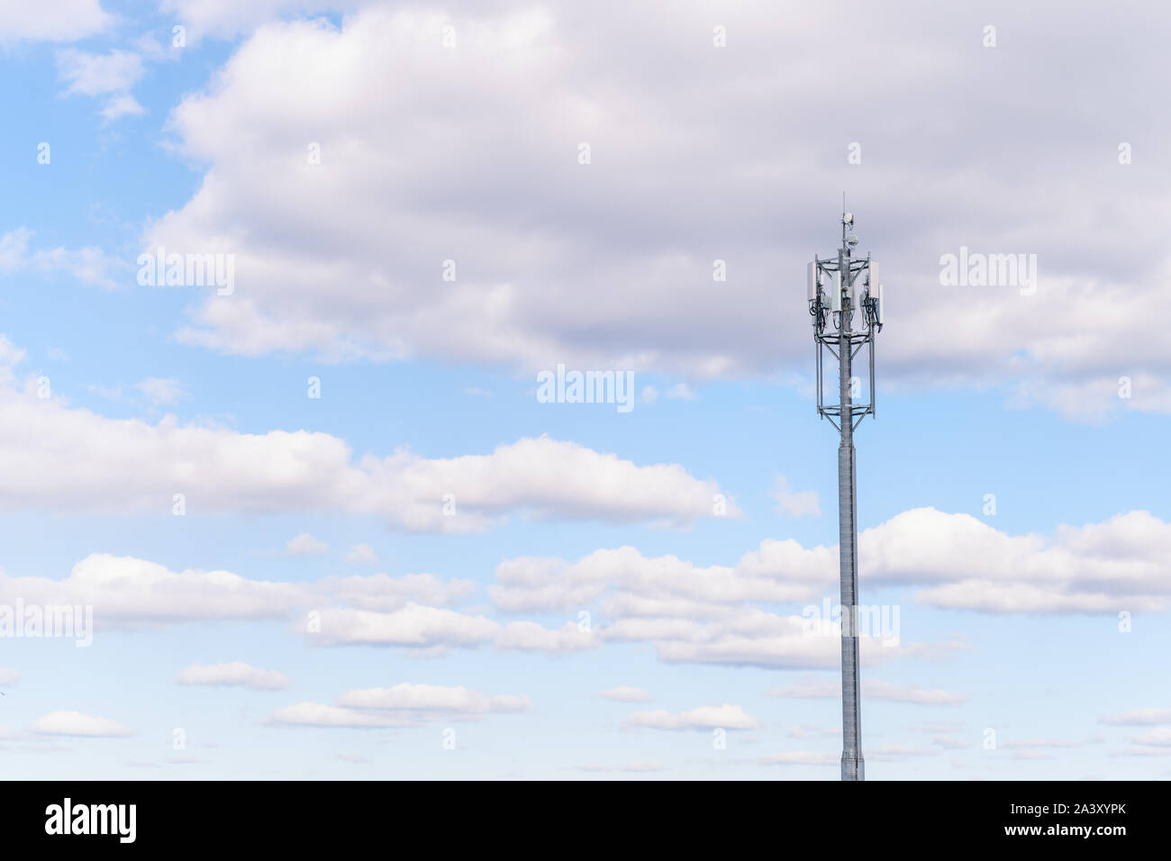 Torre cellulare contro blu cielo nuvoloso. Composizione sparse con spazio di copia Foto Stock